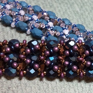 Puede incluir: Primer plano de un collar de cuentas con un patrón tejido. El collar está hecho con cuentas de color azul oscuro, morado y cobre.