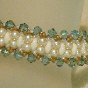 May include: A white and gold beaded bracelet with blue crystal accents. The bracelet is made with small, round beads and has a delicate, feminine look.