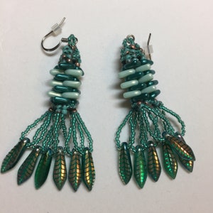 May include: A pair of teal and light blue beaded earrings with a tassel design and iridescent green leaf-shaped charms.