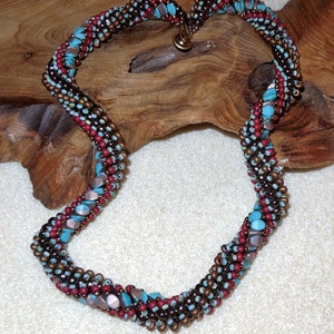 May include: A twisted necklace made with brown, red, and turquoise beads. The necklace is made with small, round beads and larger, flat beads.