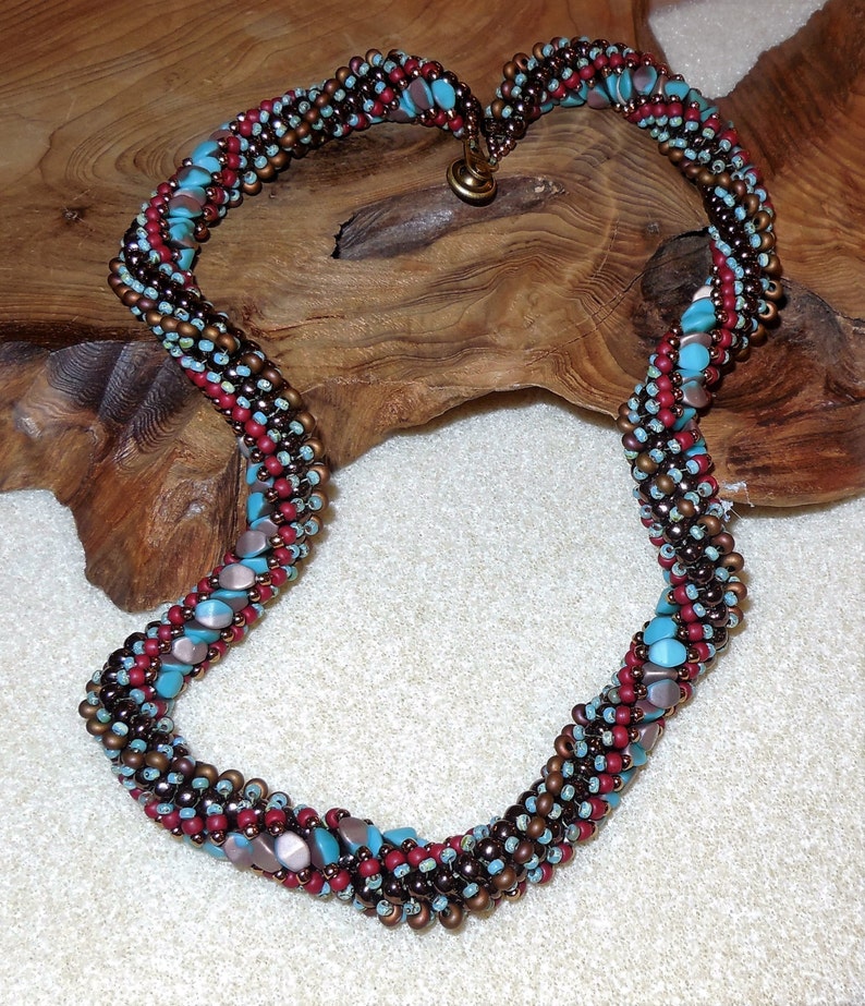 May include: A twisted necklace made with brown, red, and turquoise beads. The necklace is made with small, round beads and larger, flat beads.