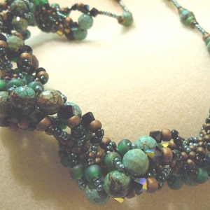 May include: A multi-strand necklace with turquoise, green, and brown beads. The necklace is made of various sizes and shapes of beads, creating a unique and textured look.