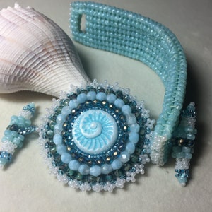 May include: A blue and white beaded bracelet with a matching pendant. The pendant features a blue and white swirl design.