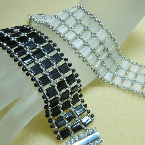 May include: Two beaded bracelets, one black and one white, with silver beads and a silver clasp.