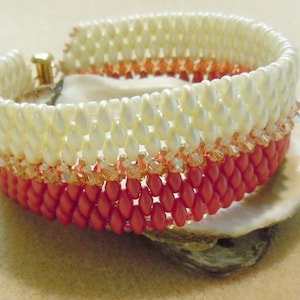 May include: A multi-colored beaded bracelet with a white, peach, and coral color scheme. The bracelet is made with small, round beads and is layered in a graduated pattern.
