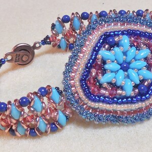 May include: A beaded bracelet with a copper wire base and a large, multi-colored, beaded flower design in the center.