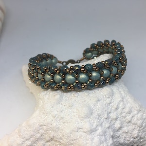 May include: A teal and copper beaded bracelet with a toggle clasp. The bracelet is made with small round beads and faceted beads.