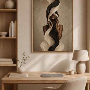 Peut inclure: Une impression d'art encadr&eacute;e repr&eacute;sentant une femme avec un tissu noir et blanc fluide. L'&oelig;uvre d'art a une palette de couleurs neutres et est expos&eacute;e dans un cadre en bois clair. L'image est dans une pi&egrave;ce avec un bureau en bois, une lampe et une chaise.