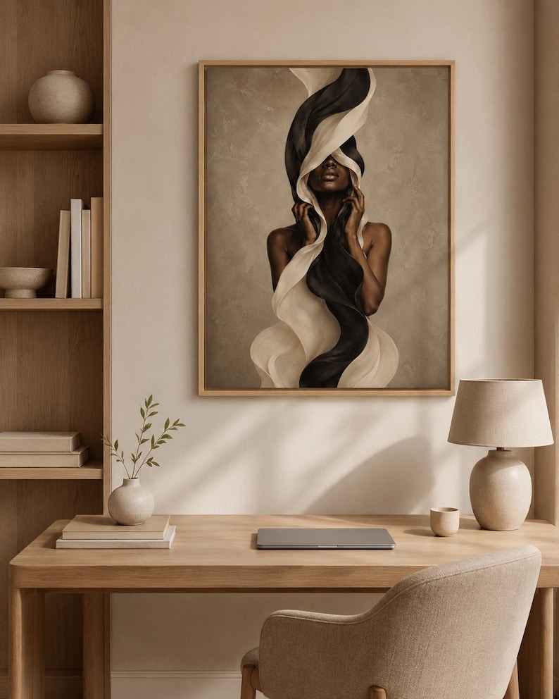 Peut inclure: Une impression d'art encadr&eacute;e repr&eacute;sentant une femme avec un tissu noir et blanc fluide. L'&oelig;uvre d'art a une palette de couleurs neutres et est expos&eacute;e dans un cadre en bois clair. L'image est dans une pi&egrave;ce avec un bureau en bois, une lampe et une chaise.