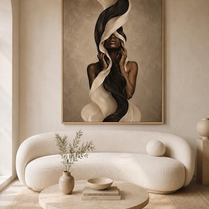 Peut inclure: Une &oelig;uvre d'art encadr&eacute;e repr&eacute;sente une femme avec un tissu noir et blanc fluide. L'&oelig;uvre est dans un cadre dor&eacute; et est suspendue au-dessus d'un canap&eacute; incurv&eacute; de couleur cr&egrave;me. Une table basse ronde avec des livres et un vase de verdure se trouve devant le canap&eacute;.