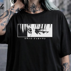 May include: Black t-shirt with a white rectangular graphic of anime eyes and Japanese text below. The shirt has short sleeves and a crew neck.