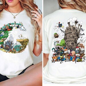 Op de afbeelding: Cr&egrave;mekleurig T-shirt met kleurrijke illustraties uit een populaire animatiefilm. Het ontwerp aan de voorkant is een cirkelvormige opstelling van personages en landschappen. De achterkant van het shirt toont een gedetailleerde afbeelding van een kasteel en diverse personages. Casual stijl.