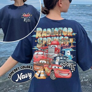 May include: Navy blue t-shirt with a graphic of characters from the film Cars, and the text "Radiator Springs" on the back. The front has a small car graphic with the word "Name". The shirt also has the words "Comfort Colors" and "Navy".