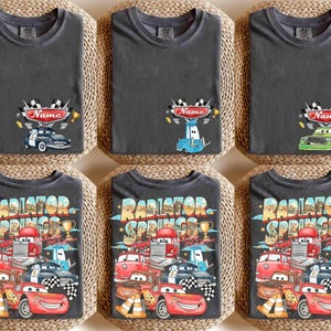 May include: Six dark grey t-shirts with car-themed designs. The top row shows a race car design with the word "Name". The bottom row features a "Radiator Springs" design with various cartoon cars.