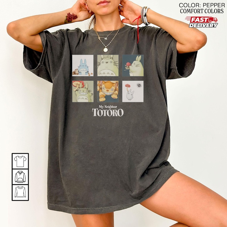 May include: Pepper-colored t-shirt featuring a six-panel graphic of characters from "My Neighbor Totoro." The design includes images of Totoro and other forest spirits. The text "My Neighbor Totoro" is printed below the graphic.