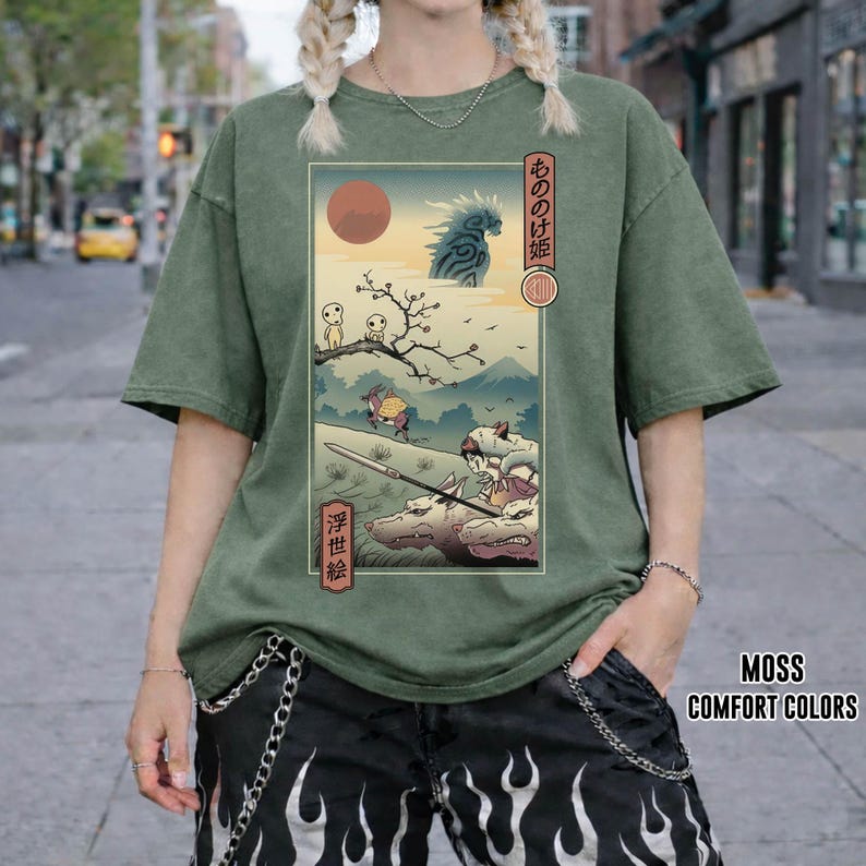 May include: Moss green comfort colors t-shirt featuring a Japanese anime-style graphic. The graphic depicts a scene with characters, a red sun, and Japanese text. The shirt has short sleeves and a relaxed fit.
