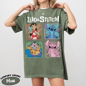 May include: Moss green t-shirt featuring the words "Lilo & Stitch" above four character illustrations. The characters include Lilo, Stitch, and other characters from the animated film. The shirt is a Comfort Colors brand.
