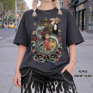 May include: Dark grey t-shirt with a vibrant anime-style illustration. The design showcases a girl with a lantern, a dragon, and other characters. The text "PEPPER COMFORT COLORS" is printed on the lower right.