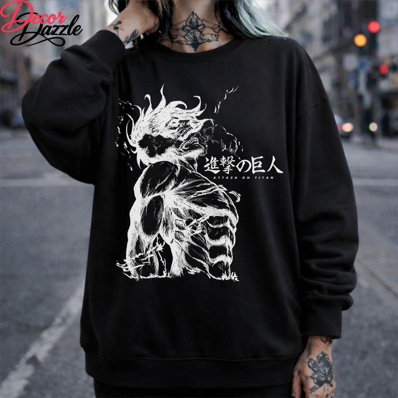 May include: Black sweatshirt featuring a white graphic of a muscular figure with spiky hair and the Japanese text "Attack on Titan." The design is a detailed illustration. The sweatshirt is a casual garment.