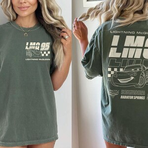 Puede incluir: Camiseta verde con gr&aacute;ficos de Rayo McQueen. La parte delantera muestra "LMQ 95" con una ilustraci&oacute;n de coche y "Lightning McQueen". La parte trasera presenta un dise&ntilde;o m&aacute;s grande con "Lightning McQueen", "Radiator Springs" y el n&uacute;mero "95".