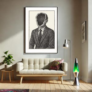 May include: Black and white illustration of a person in a suit with a hole in their head. The illustration is framed and hanging on a wall above a light-colored couch.