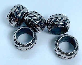 May include: Six silver metal rings with a braided design. The rings are all the same size and have a smooth, polished finish.