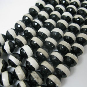 May include: A strand of black and white agate beads. The beads are round and have a striped pattern.