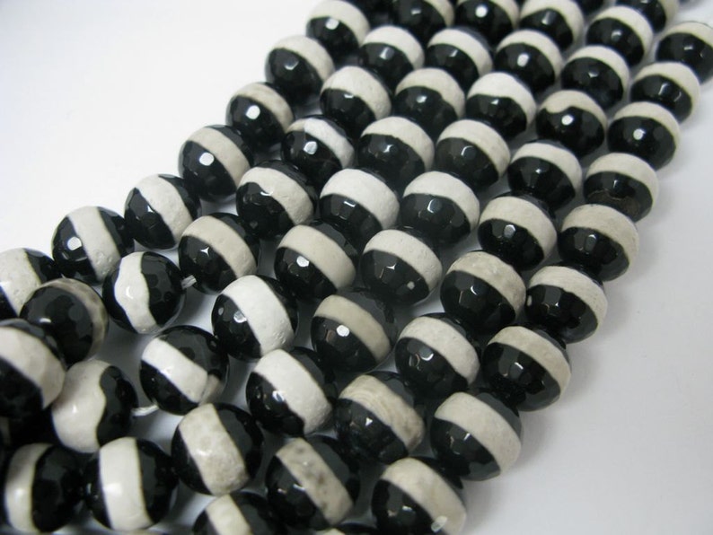 May include: A strand of black and white agate beads. The beads are round and have a striped pattern.