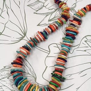 May include: A necklace composed of numerous flat, disc-shaped beads in a vibrant array of colors including turquoise, orange, yellow, red, purple, green, and white. The beads are strung together in a continuous strand, creating a multi-colored pattern.