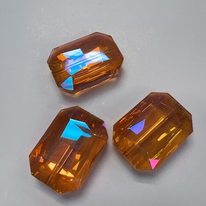 May include: Three iridescent amber glass beads with a rectangular shape.