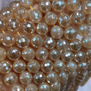 May include: A strand of iridescent, faceted, peach-colored gemstone beads. The beads are round and have a honeycomb pattern.