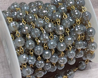 May include: A spool of gray faceted glass beads strung on a gold chain. The beads are approximately 6mm in diameter and have a faceted finish. The chain is made of gold-plated metal.
