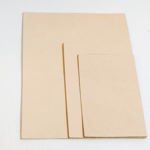 May include: Three pieces of beige leather in different sizes. The leather is smooth and has a natural grain.