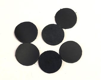 May include: A collection of six black, circular leather patches. The patches are arranged on a white background, with varying textures visible on their surfaces. The leather appears to be of different finishes, some smooth and others more textured.