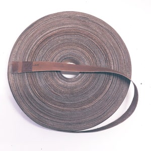 Puede incluir: Un rollo de papel de lija marrón con el número "235" escrito en él.