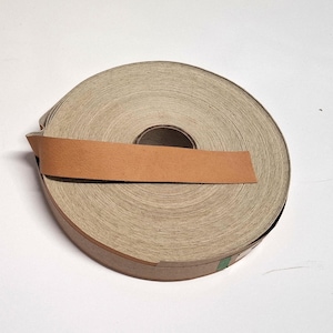 May include: A roll of brown paper tape with a tan coloured edge. The tape is wound around a cardboard core.