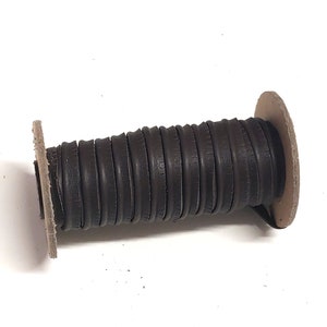 May include: A spool of brown leather cord wrapped around a cardboard core.