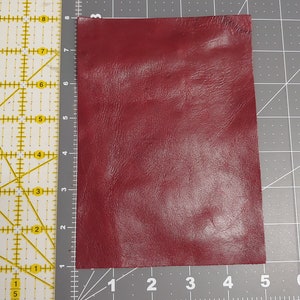 May include: A piece of burgundy leather, measuring approximately 5 inches by 4 inches.
