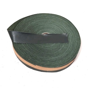 May include: A roll of green leather trim with a brown edge. The leather is rolled up and the edge is visible.