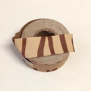 May include: A roll of brown leather trim with a zebra stripe pattern. The leather is rolled up on a cardboard core.
