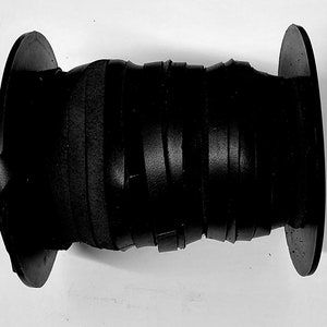 Może przedstawiać: Szpula czarnego sznurka skórzanego owinięta wokół dwóch czarnych plastikowych szpul.