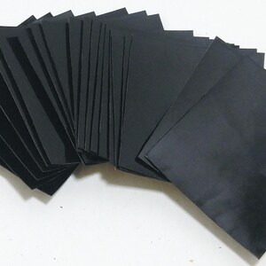 May include: A collection of multiple rectangular black sheets arranged in a fanned-out stack. Each sheet is solid black with a smooth, matte finish and sharp, clean edges. The stack is layered to show the individual pieces overlapping in a semi-circle.