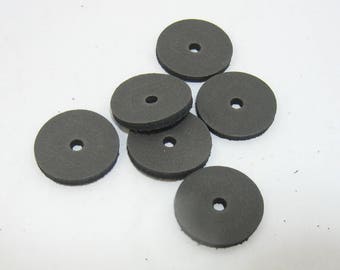 May include: Six black leather washers with a hole in the center. The washers are arranged in a pile.