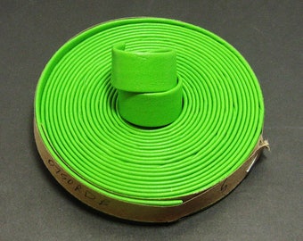 May include: A roll of bright green leather cord, coiled and wrapped around a brown cardboard core. The cord is approximately 6 mm wide and has a textured surface. The label on the core reads "0.150 RD".