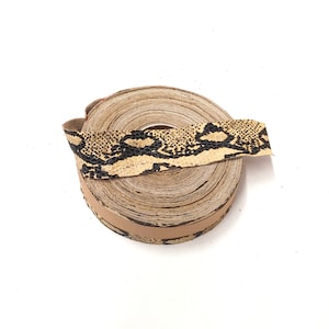 May include: A roll of brown leather trim with a black and tan snakeskin pattern.