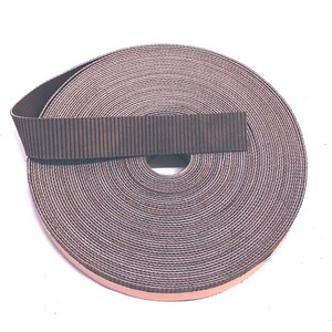 Może przedstawiać: Rolka brązowej taśmy z tektury falistej z jasnobrązową klejącą stroną.