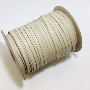 May include: A spool of off-white vinyl trim, wound around a cardboard core.