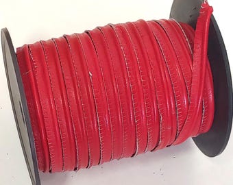 May include: A spool of bright red leather cord wrapped around a black plastic reel. The cord has a smooth, rounded surface and is wound in multiple tight, parallel rows across the length of the spool, showing a consistent vibrant red color.
