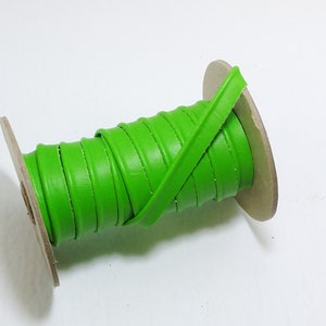 May include: A spool of bright green leather cord, wound around a cardboard core.