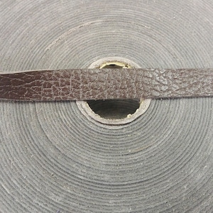 Może przedstawiać: Rolka brązowego sznurka skórzanego z fakturowaną powierzchnią.